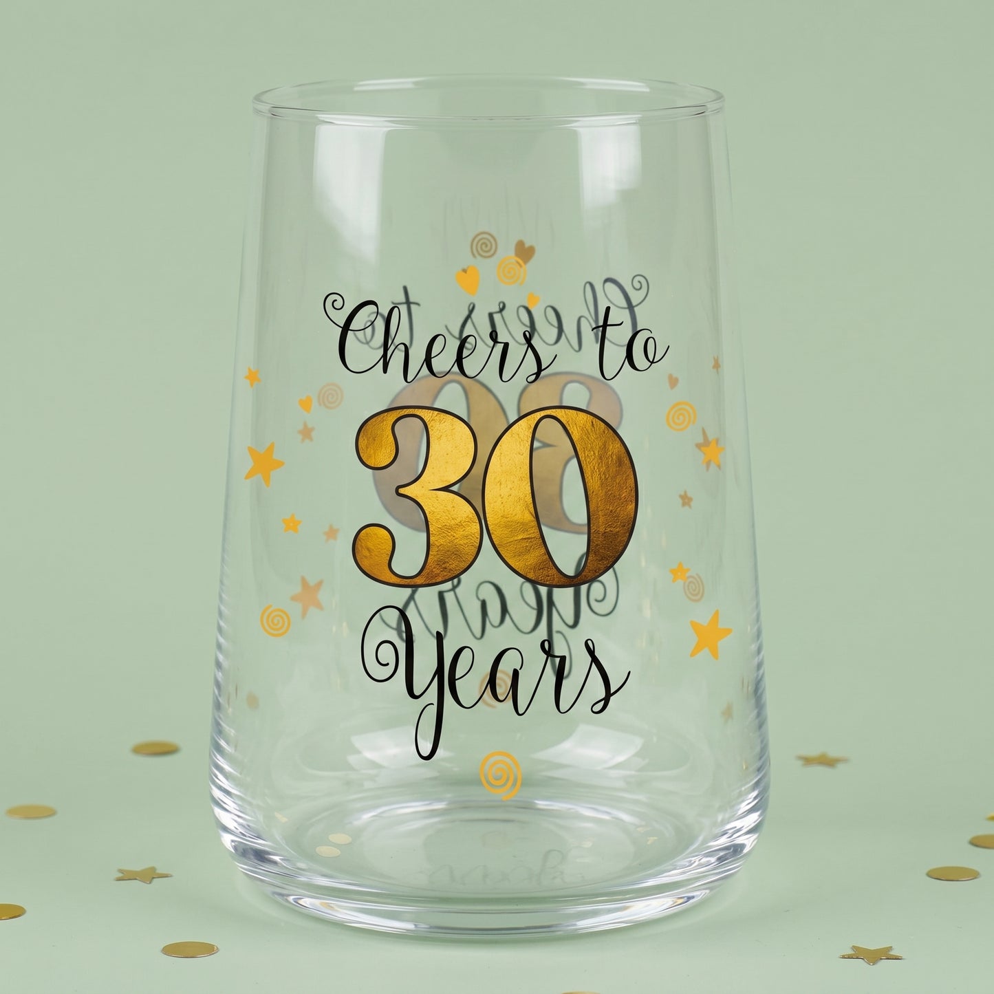 Leeres Trinkglas mit Cheers to 30 Years Aufdruck, goldener 30 und Sternen auf grünem Hintergrund