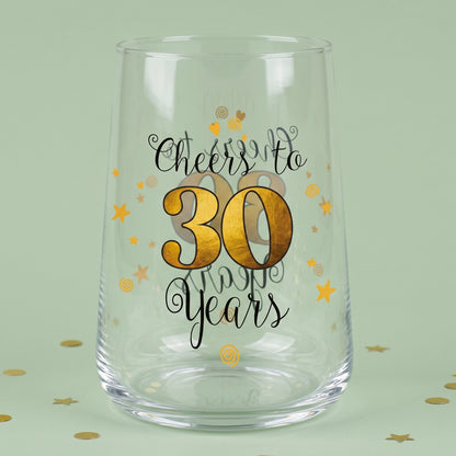 Leeres Trinkglas mit Cheers to 30 Years Aufdruck, goldener 30 und Sternen auf grünem Hintergrund