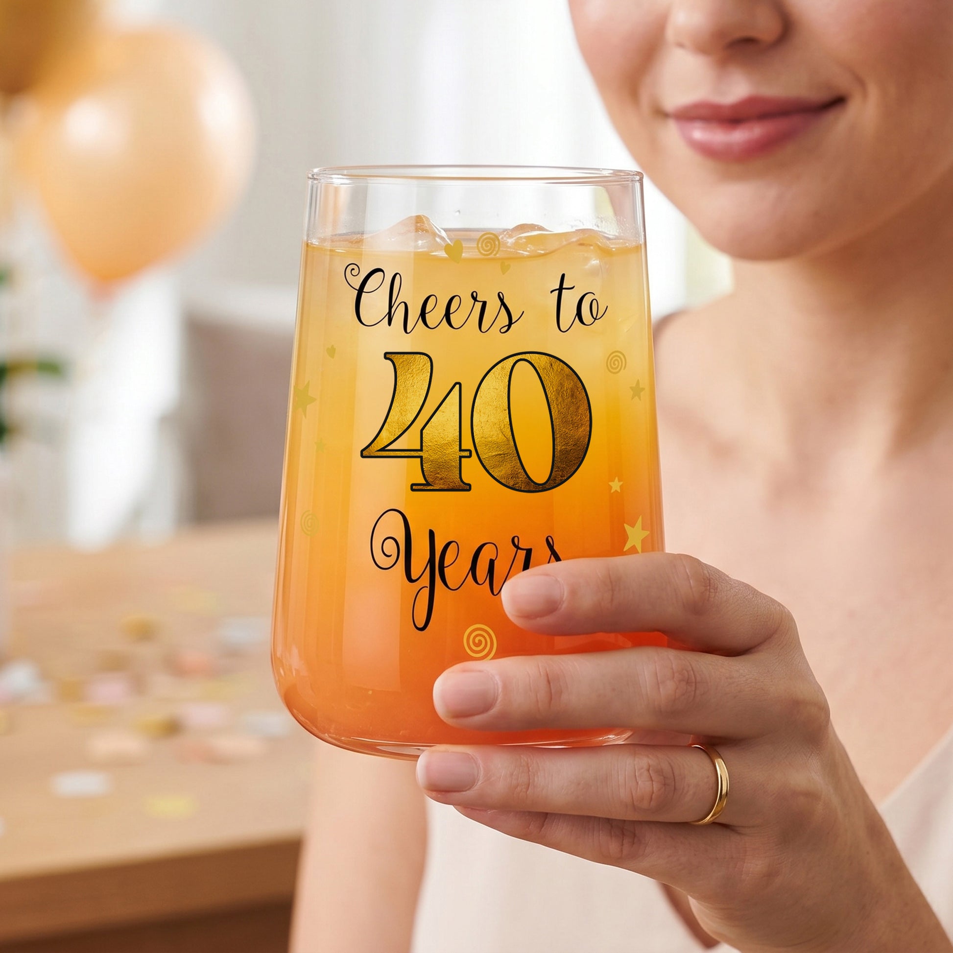 Trinkglas mit Cheers to 40 Years Aufdruck wird von einer Frau gehalten