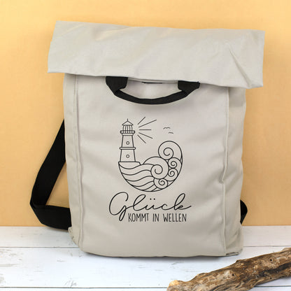 Beiger 2-in-1 Rucksack mit Leuchtturm, Wellen Motiv und Spruch Glück kommt in Wellen vor gelbem Hintergrund