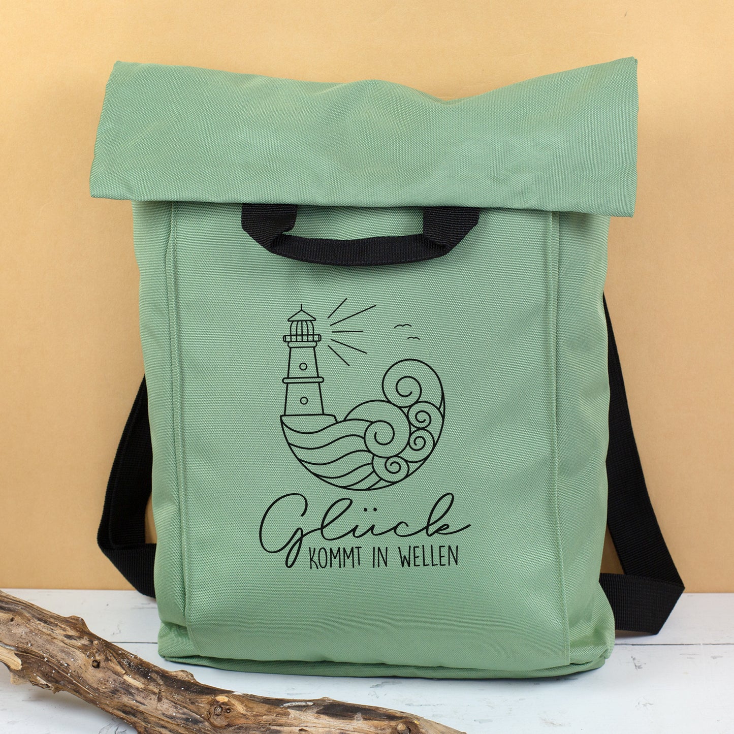Jadegrüner Rucksack mit schwarzem Leuchtturm Motiv und Spruch Glück kommt in Wellen als leichte Urlaubstasche