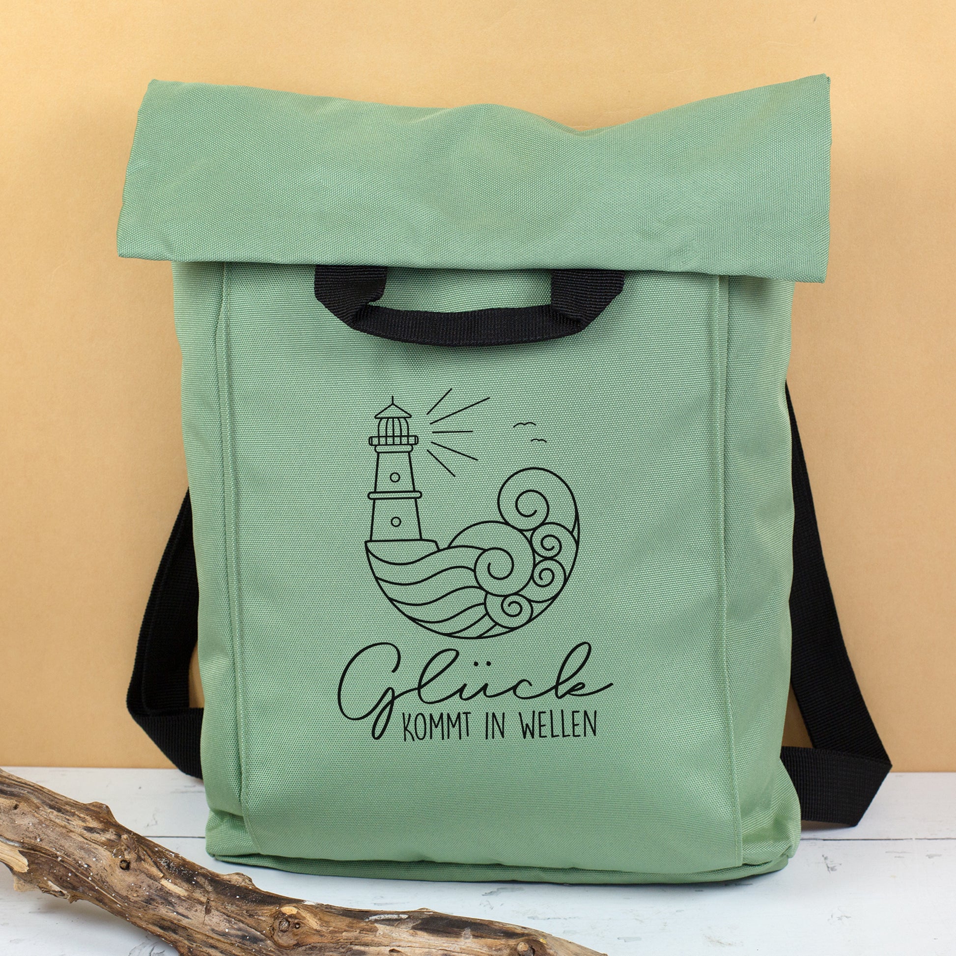 Jadegrüner Rucksack mit schwarzem Leuchtturm Motiv und Spruch Glück kommt in Wellen als leichte Urlaubstasche