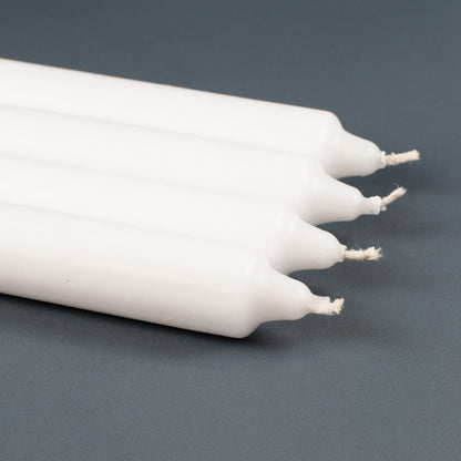 Nahaufnahme der weißen Stabkerzen aus dem Adventskerzen-Set, liegend auf grauem Untergrund.