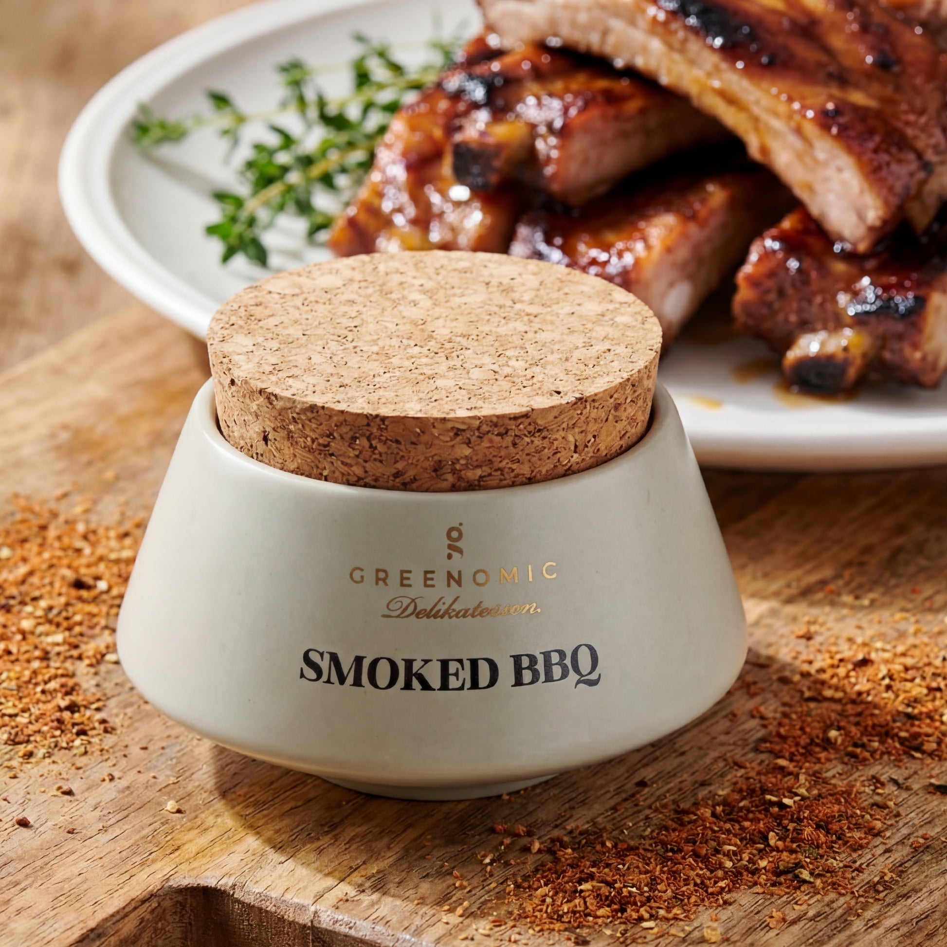 Premium Smoked BBQ Gewürzmischung im Keramiktopf mit Rippchen und Kräutern im Hintergrund