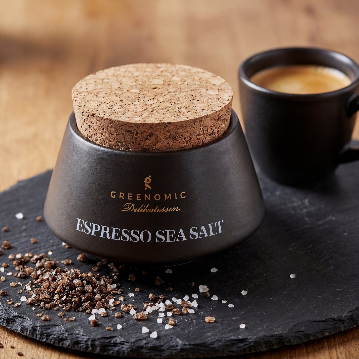Premium Meersalz mit gemahlenem Kaffee im Keramikbehälter neben Espressotasse