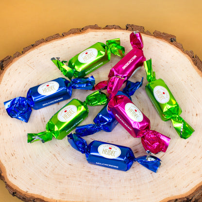 Acht einzeln verpackte Schokoladenstücke mit Milchcremefüllung in Blau Grün und Pink