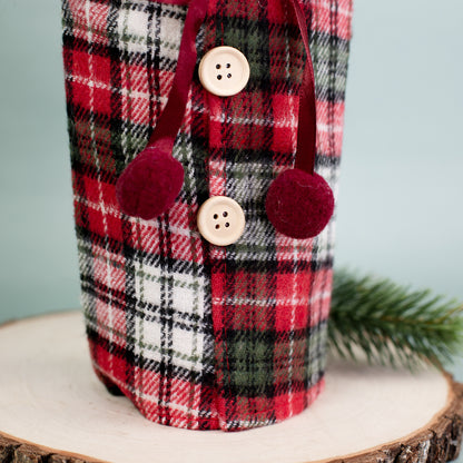 Detailaufnahme der Knopfleiste der karierten Flaschenverpackung mit roten Bommeln und Holzknöpfen.