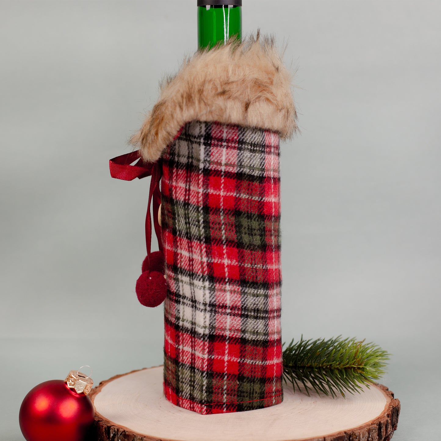 Kariertes Flaschenmäntelchen von der Seite, Pelzkragen oben, rote Schleifen und Knöpfe vorn.