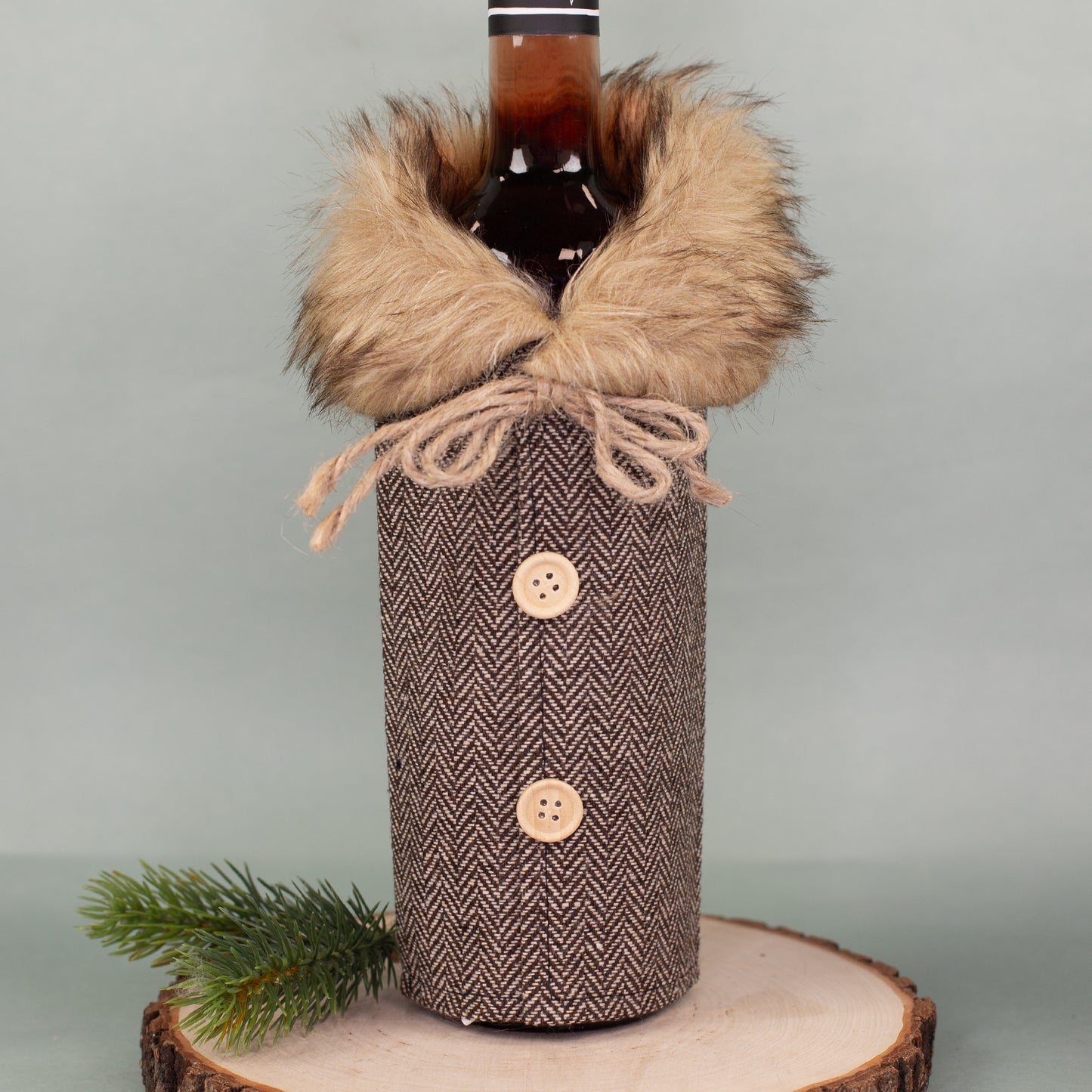 Flaschen Geschenkverpackung in Mantel-Optik, braun gemustert, mit Pelzkragen und Kordel, auf Holzplatte dekoriert.