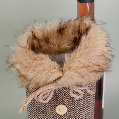 Nahaufnahme des Pelzkragens der braunen Flaschen Geschenkverpackung in Mantel-Optik mit Kordel und Knöpfen.