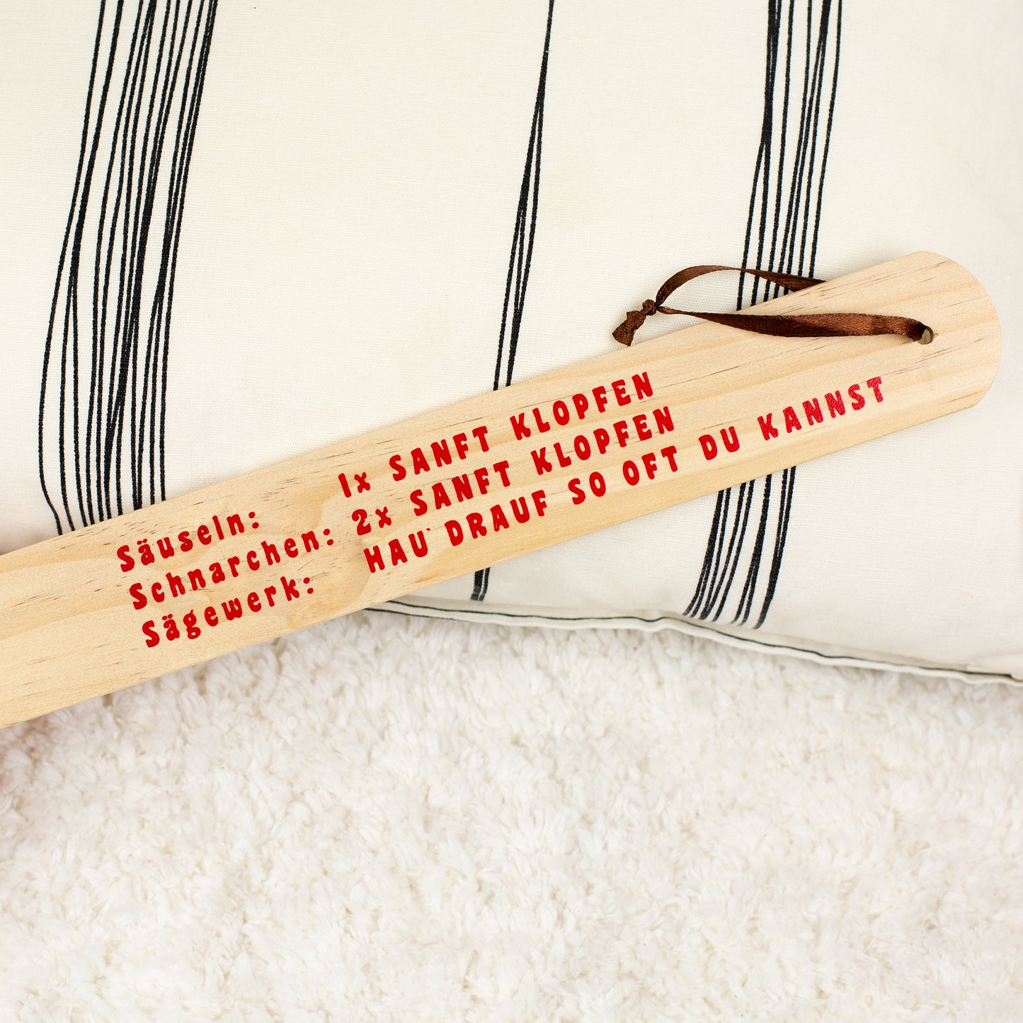 Detailaufnahme des Holzgriffs mit rotem Text und integrierter Aufhängung am Griffende