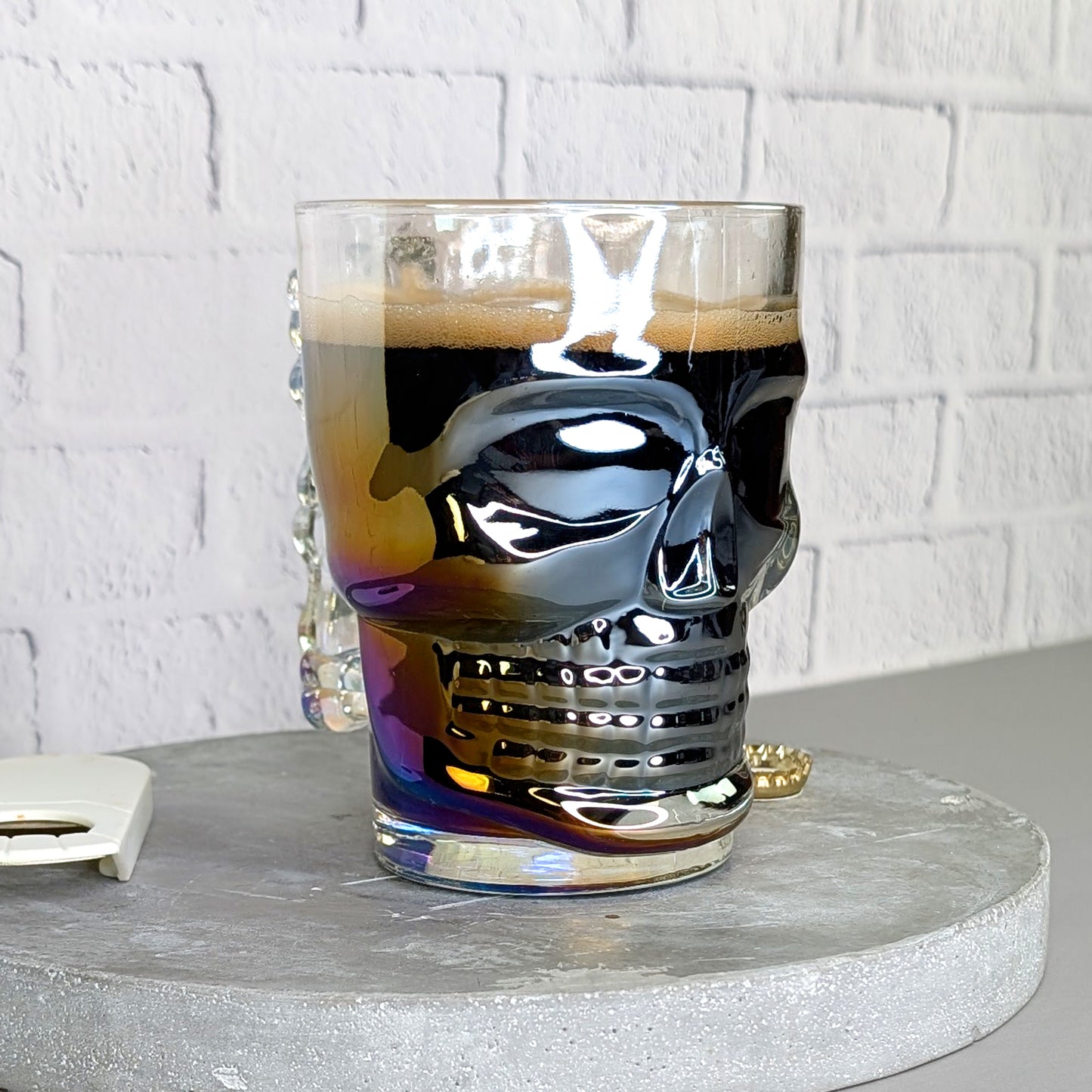 Totenkopfglas leicht schräg von vorne gefüllt mit dunklem Bier und irisierendem Effekt
