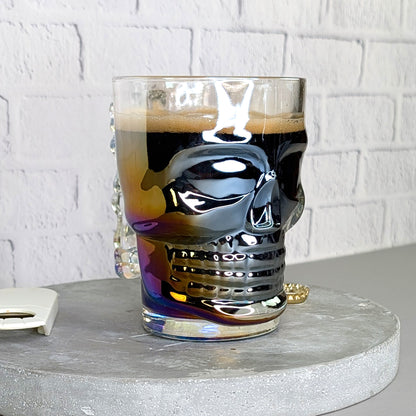 Totenkopfglas leicht schräg von vorne gefüllt mit dunklem Bier und irisierendem Effekt