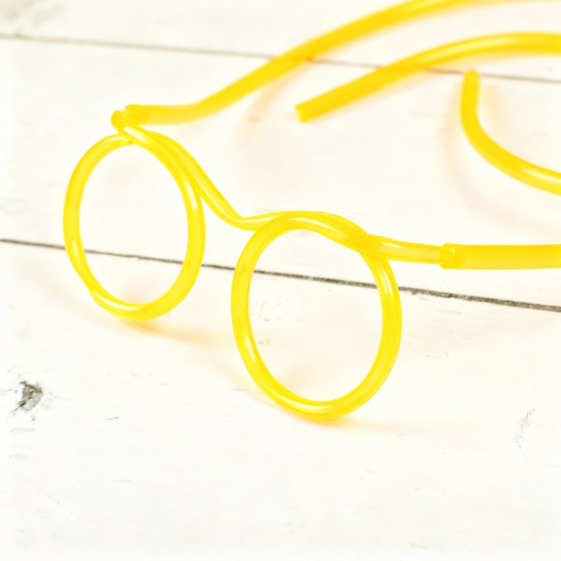 Gelbe Trinkschlauch-Brille – Nahaufnahme der Schlauchführung und Brillenringe auf hellem Untergrund
