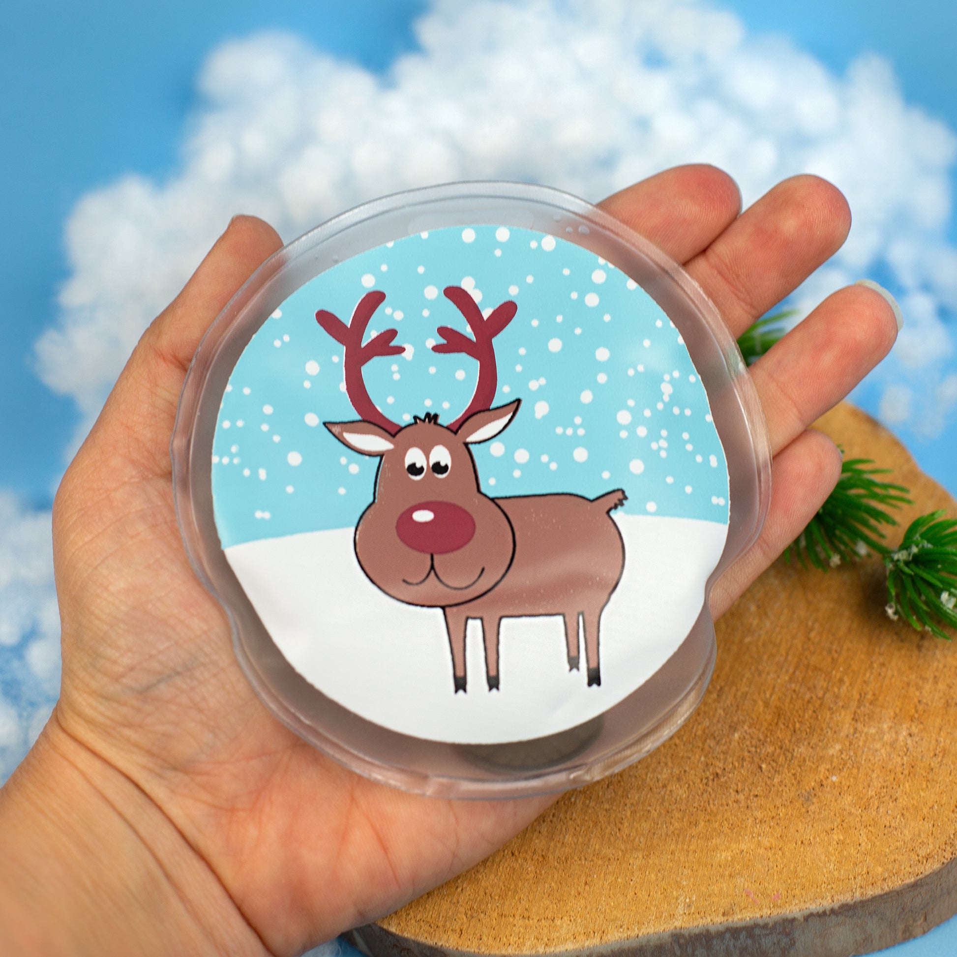 Rentier-Handwärmer in der Hand gehalten, Vorderseite mit Schneefallmotiv