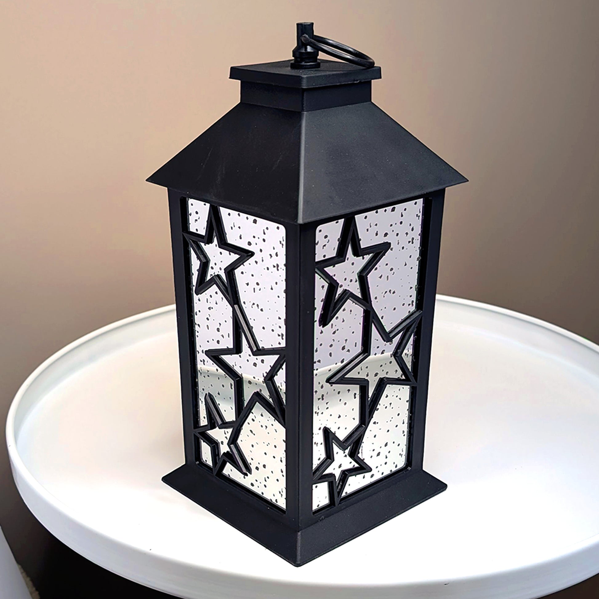 LED-Weihnachtslaterne mit Spiegelwänden und Sternendesign auf weißem Tisch