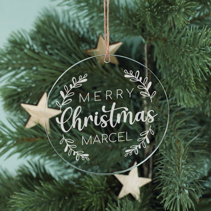 Personalisierter Weihnachtsbaumanhänger aus Acryl mit „Merry Christmas“, Name Marcel und Juteband zwischen Tannenzweigen