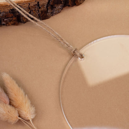 Nahaufnahme der Aufhängung einer transparenten Acryl Weihnachtskugel mit Loch und geknotetem Juteband