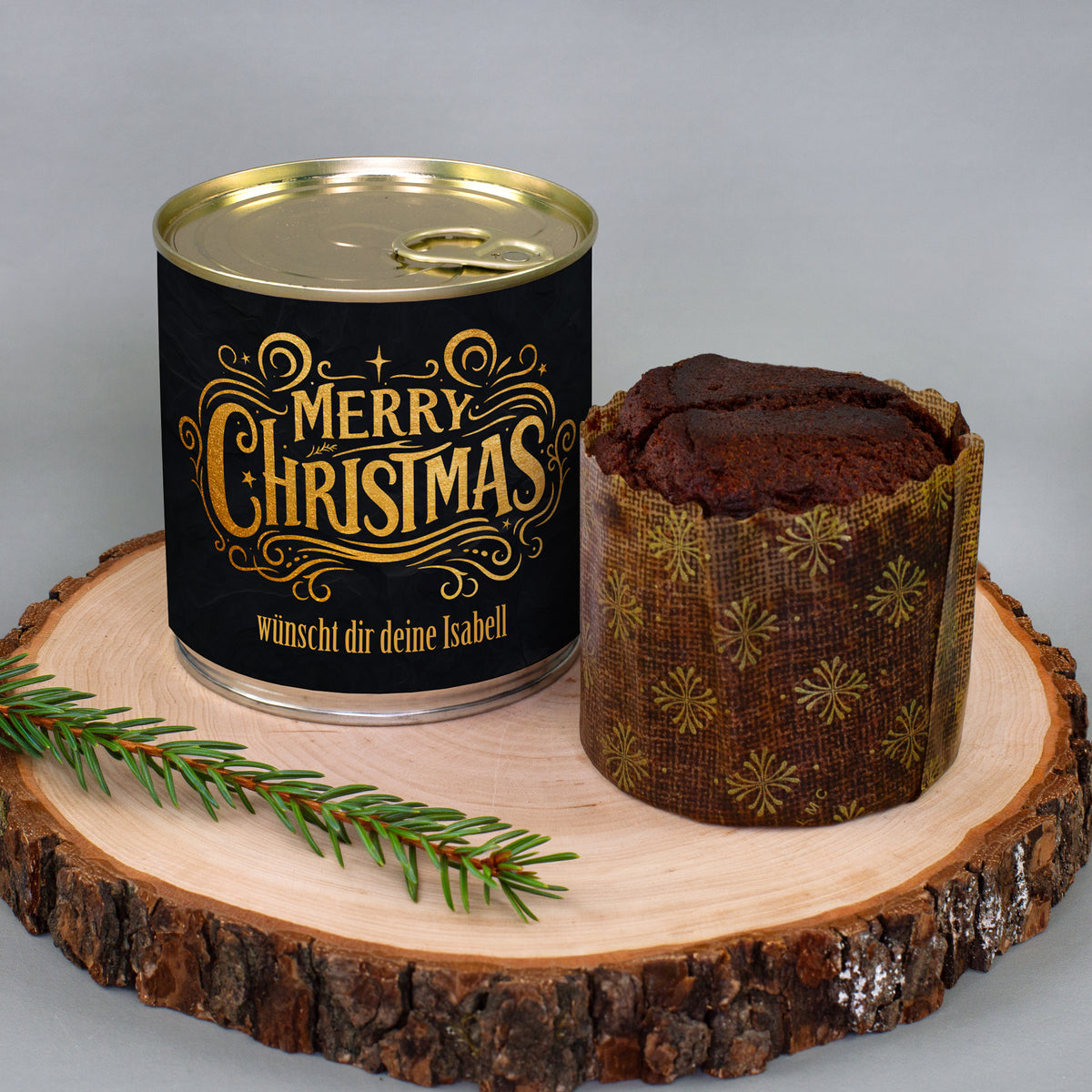 Personalisierter Brownie-Dosenkuchen zu Weihnachten mit schwarzem Merry-Christmas-Motiv und Wunschtext neben ausgepacktem Kuchen auf Holzscheibe