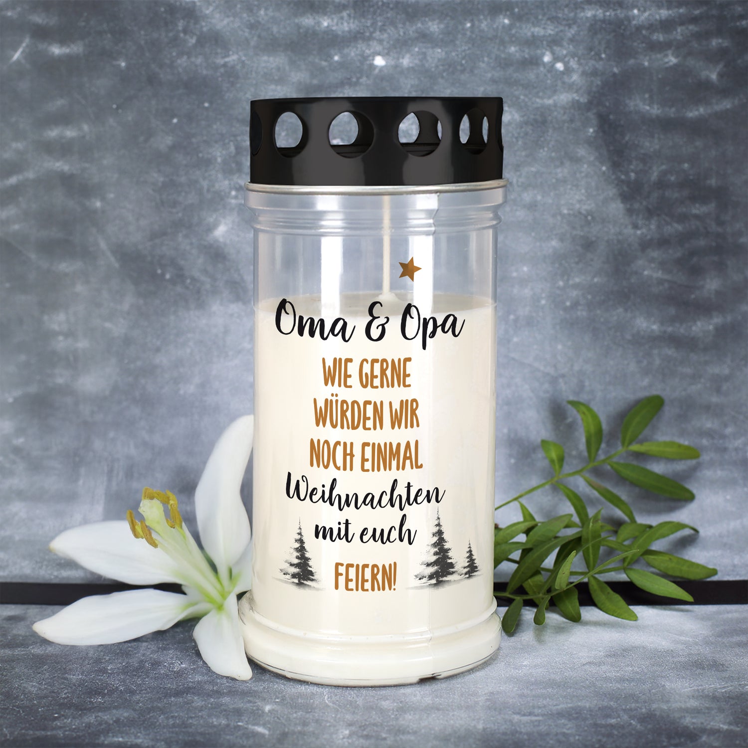 Weihnachts-Grablicht mit Aufdruck „Oma & Opa – Wie gerne würden wir noch einmal Weihnachten mit euch feiern!“ neben weißer Lilie