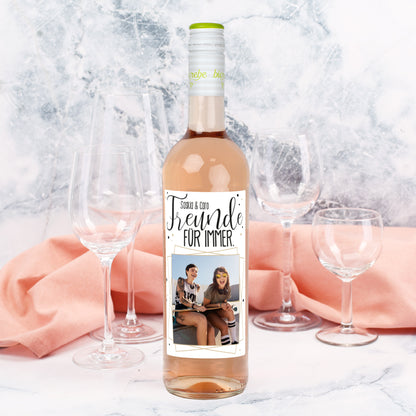 Personalisierte Roséweinflasche mit Etikett „Freunde für immer“ und Foto, dekoriert mit Gläsern und Stoff