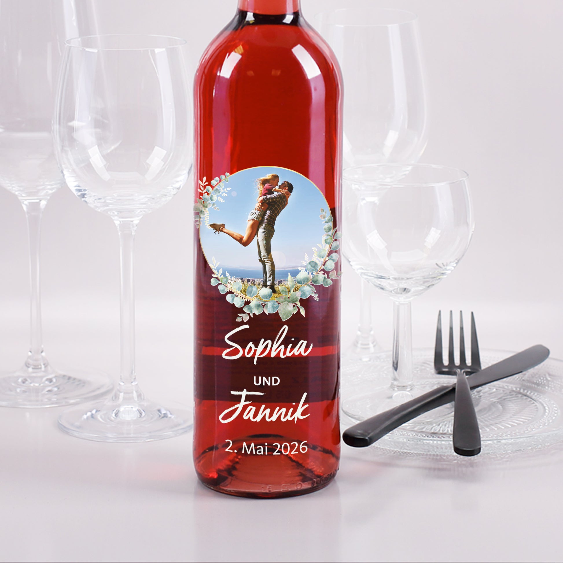 Personalisierte Roséweinflasche mit Foto im Eukalyptuskranz, Namen „Sophia und Jannik“ und Hochzeitsdatum.