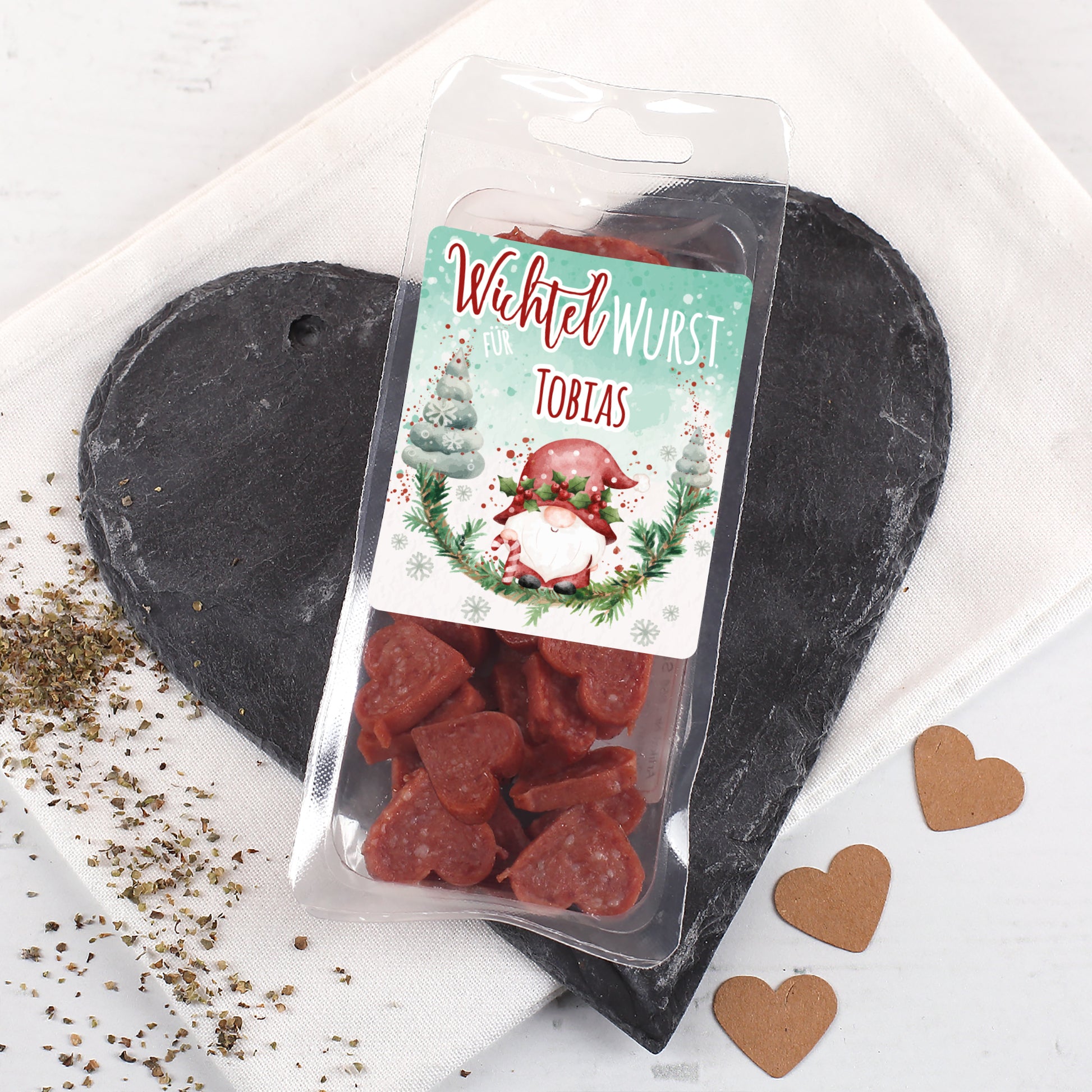 Wichtel-Wurst mit winterlichem Motiv und personalisierter Namensfläche, gefüllt mit Salamiherzen.
