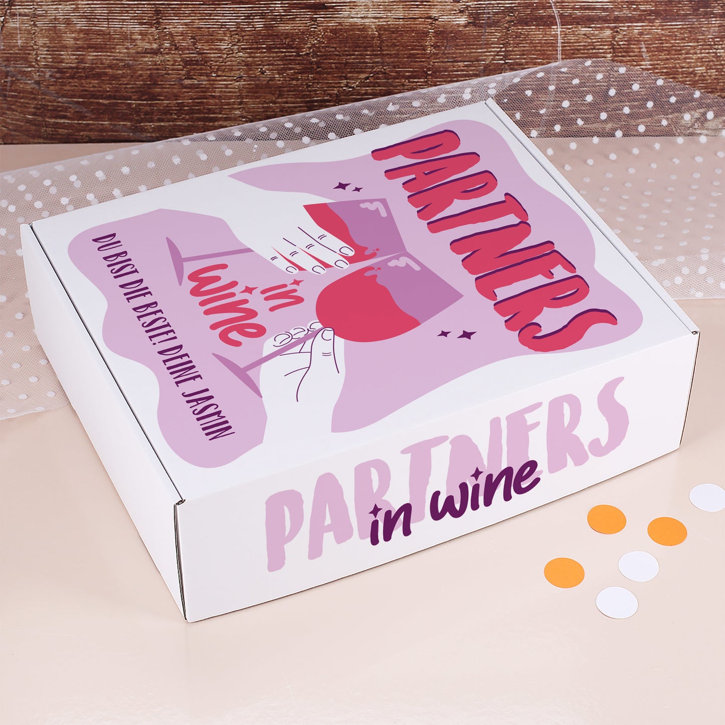 Geschenkbox mit Aufschrift „Partners in Wine“ in Rosa- und Lilatönen, dekoriert mit Konfetti und persönlicher Widmung