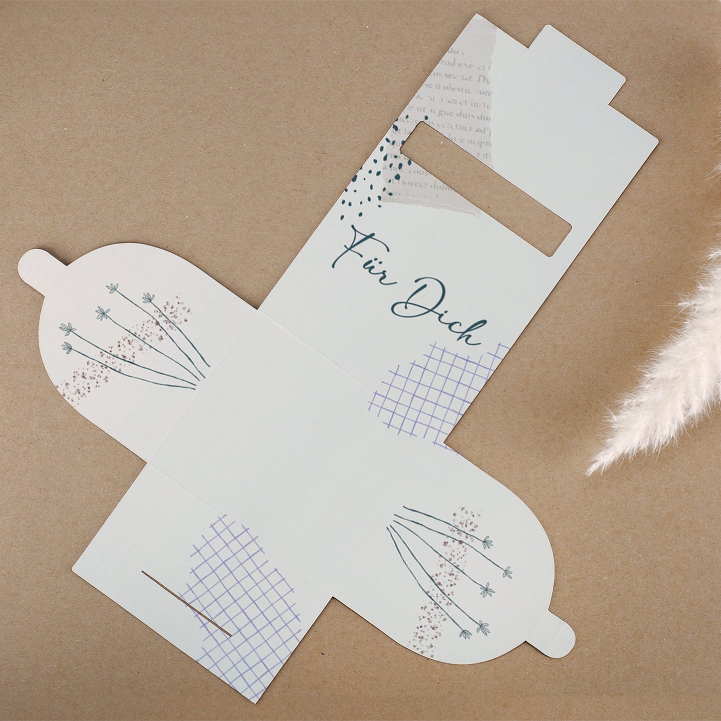 Flachliegende, aufgefaltete Geschenkverpackung aus Karton mit der Aufschrift „Für Dich“. Sichtbar sind das florale und grafische Design in zarten Farben sowie die ausgestanzten Elemente zum Zusammenstecken der Box.