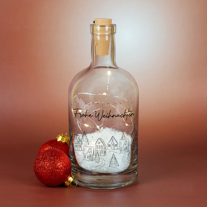 Dekorative LED-Karaffe mit Winterdorf-Motiv, Kunstschnee und warmweißer Beleuchtung, personalisiert mit „Frohe Weihnachten“.
