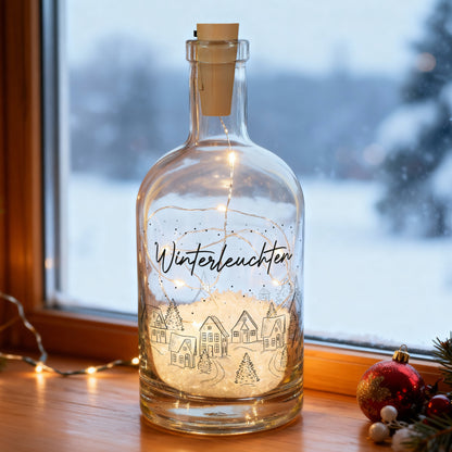 Leuchtende Winter-Karaffe mit LED-Lichterkette und Wunschtext „Winterleuchten“ auf Fensterbank im Schneeambiente.