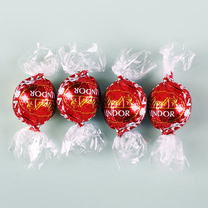 Vier rote Lindor-Kugeln einzeln verpackt, Vollmilchschokolade mit zartschmelzender Füllung als Bestandteil des Geschenksets.