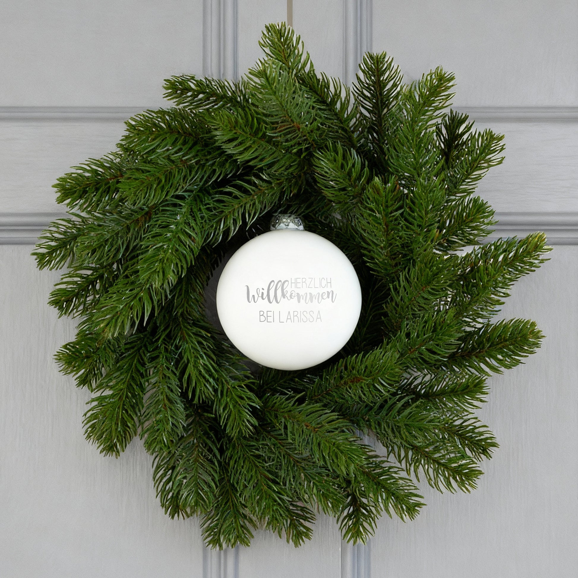 Türkranz mit weißer Willkommens-Kugel an grauer Haustür dekoriert