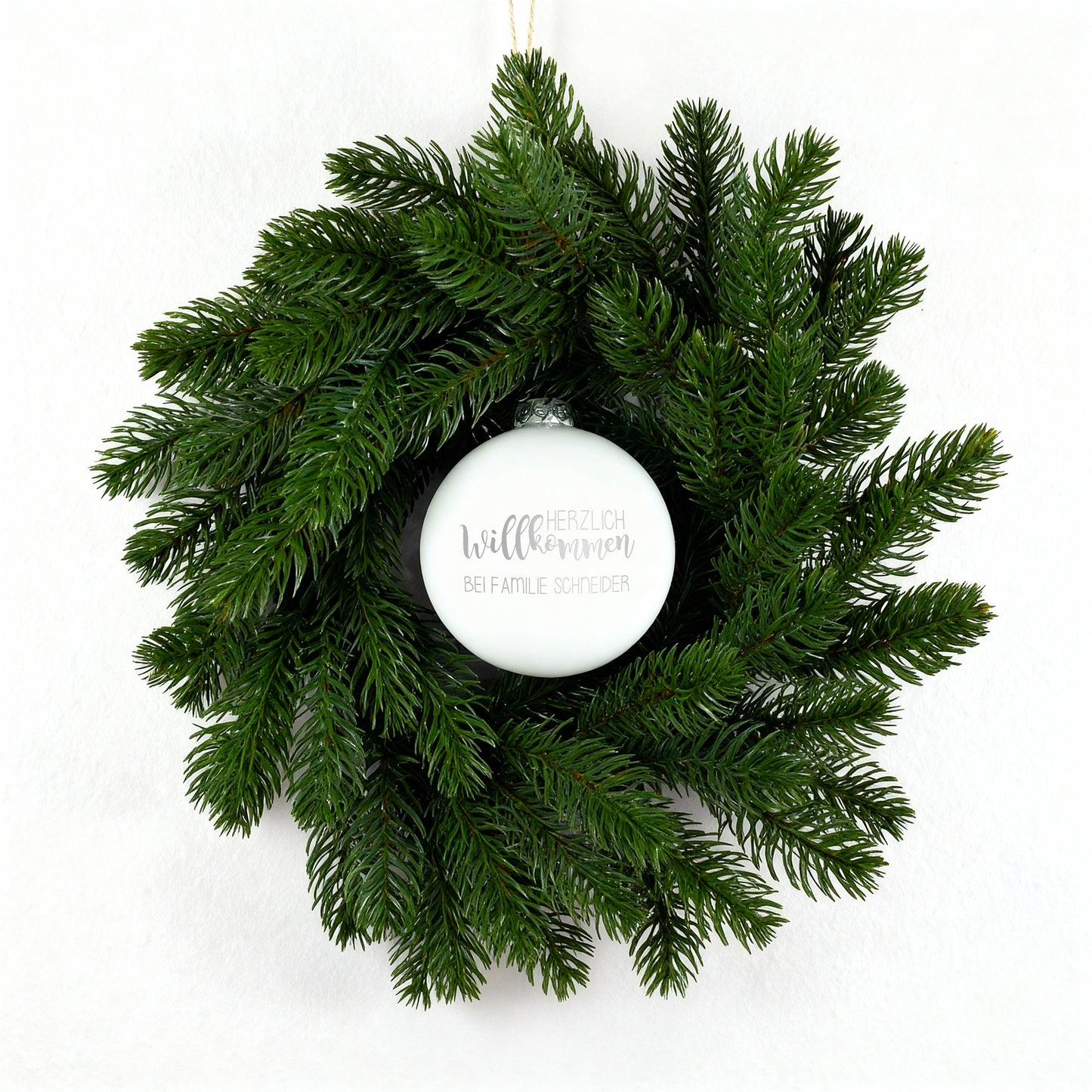 Weihnachts-Türkranz mit weißer gravierter Kugel „Herzlich willkommen“ auf weißem Hintergrund