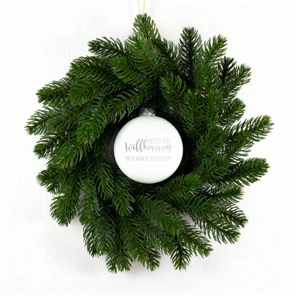 Weihnachts-Türkranz mit weißer gravierter Kugel „Herzlich willkommen“ auf weißem Hintergrund