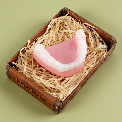 Rosa-weiße Gebissseife in kleiner Holzschale mit Füllmaterial als lustiger Inhalt im Ruhestand Geschenkset