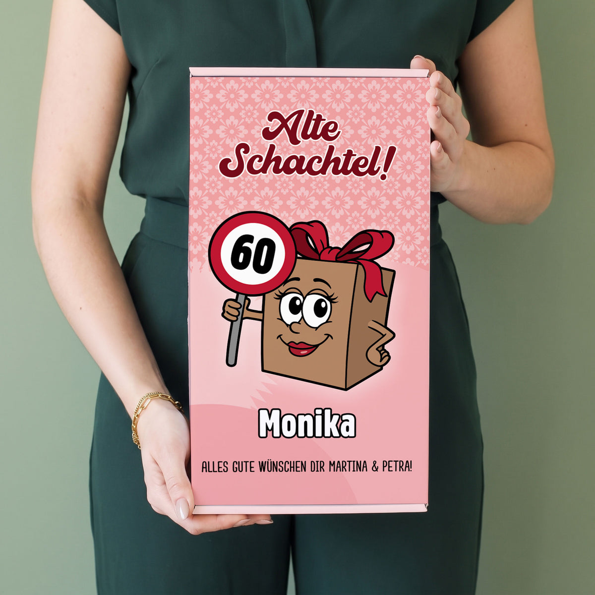 Frau hält personalisierte Geschenkbox „Alte Schachtel!“ mit Name Monika und Alter 60 in den Händen