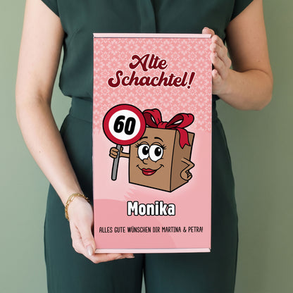 Frau hält personalisierte Geschenkbox „Alte Schachtel!“ mit Name Monika und Alter 60 in den Händen