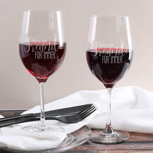 Zwei gravierte Weingläser mit der Aufschrift „Freunde für immer“ und Namen Miriam & Caro, gefüllt mit Rotwein