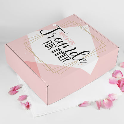 Rosa Geschenkbox „Freunde für immer“ mit goldenen Linien und den Namen Miriam & Caro, daneben Rosenblätter