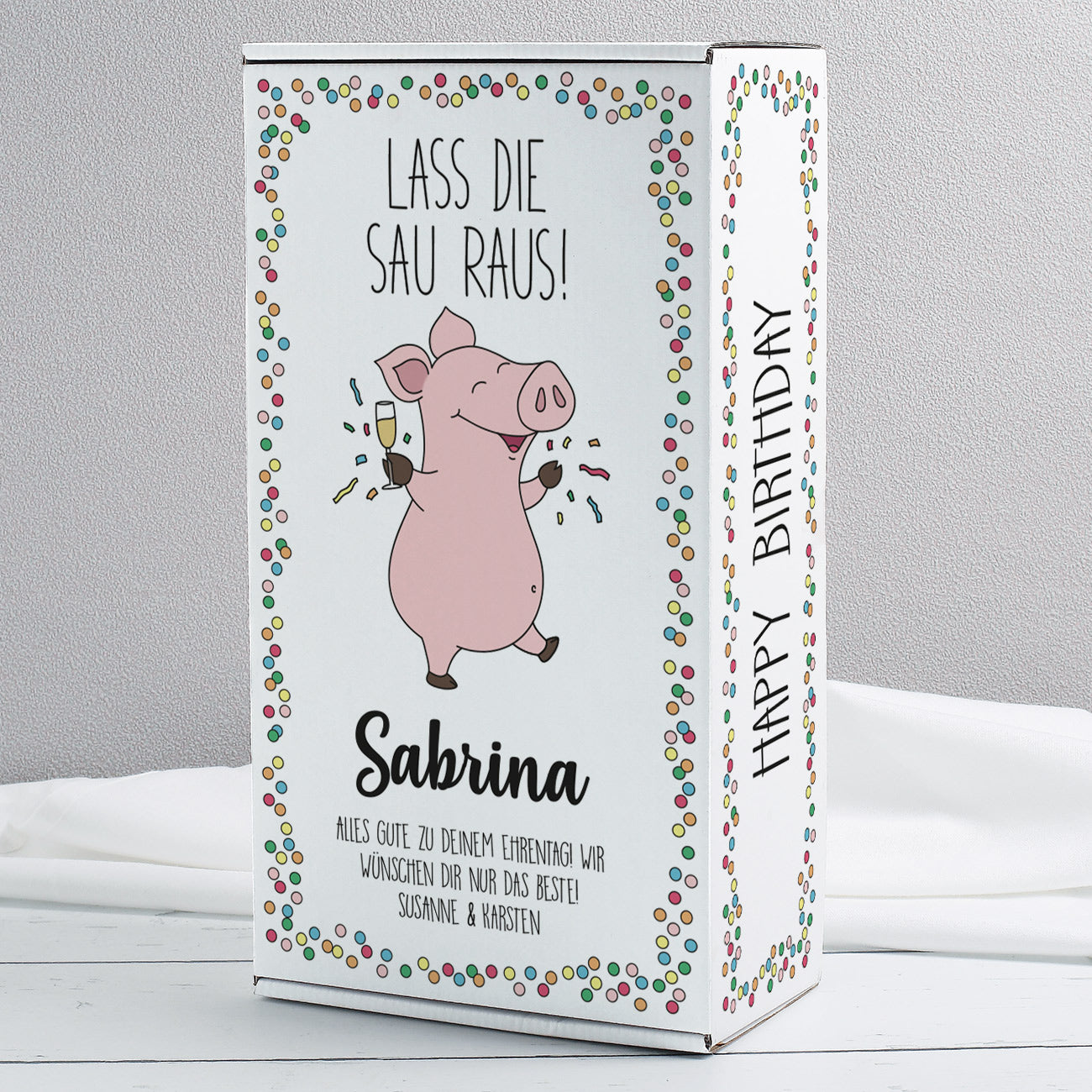 Geschenkbox „Lass die Sau raus!“ mit Schwein-Motiv und Name Sabrina, bunte Konfetti-Umrandung