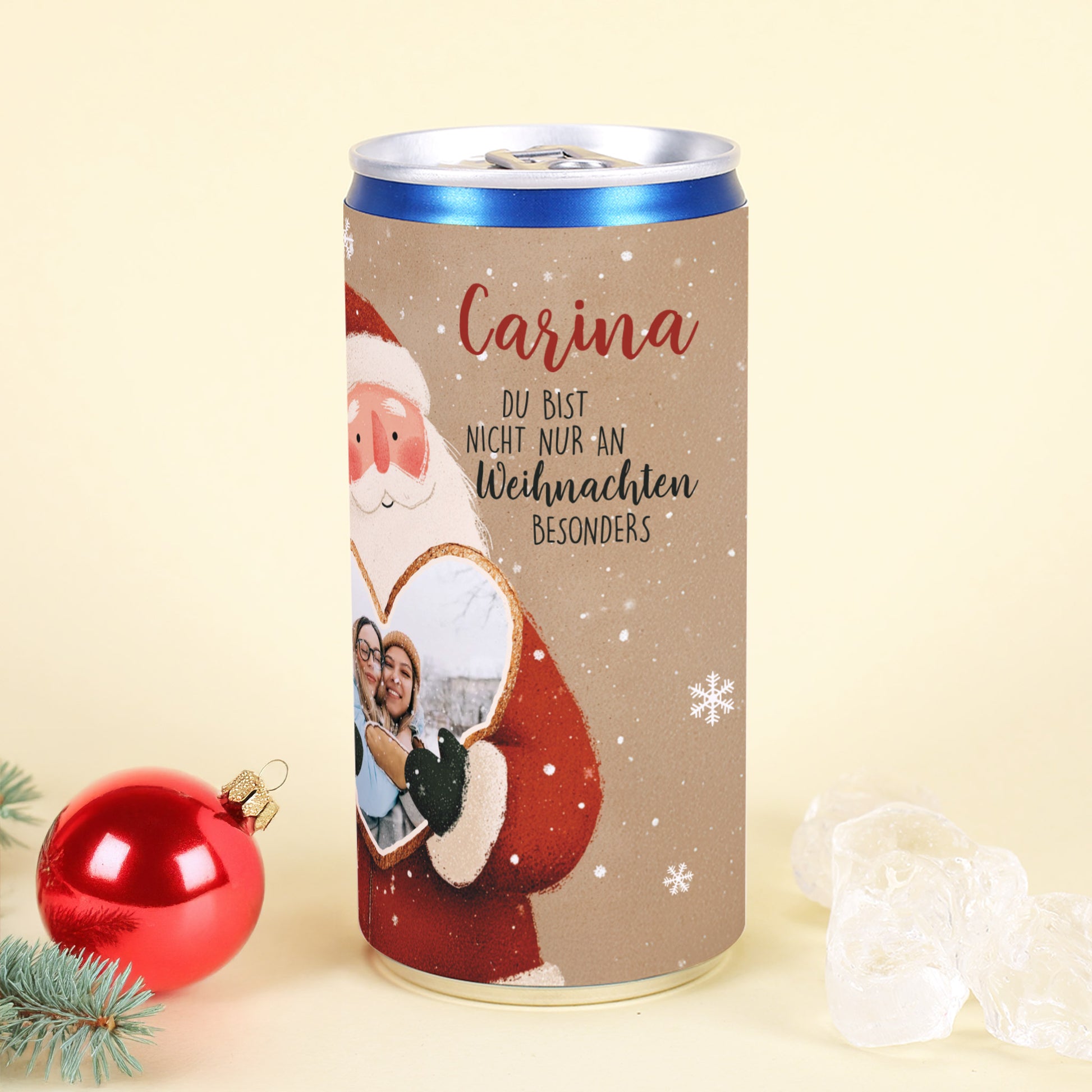 Personalisierte Secco-Dose mit Name „Carina“, Weihnachtsmann hält Herz mit Foto, dekoriert mit roter Kugel und Eisstücken.
