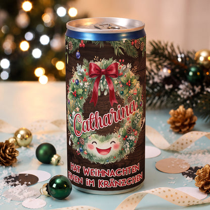 Personalisierte Secco-Dose mit Name Catharina, Weihnachtskranz und Spruch „Hat Weihnachten einen im Kränzchen“ zwischen Weihnachtsdekoration