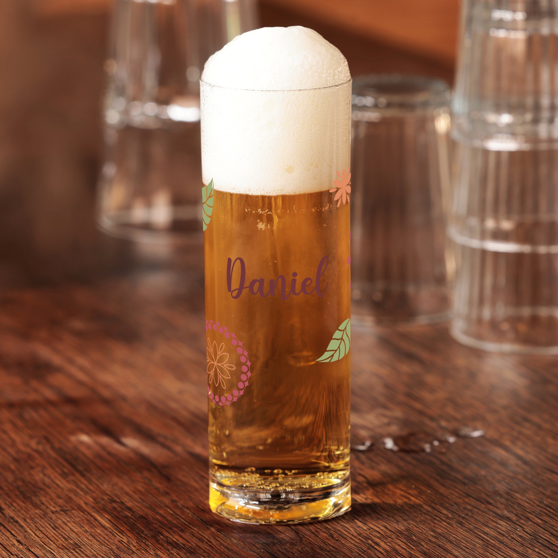 Kölschglas mit Name Daniel und floralen Elementen, gefüllt mit Bier und Schaumkrone