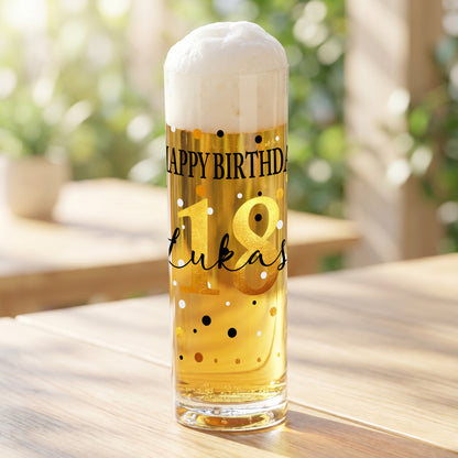 Personalisiertes Kölschglas mit Geburtstagsmotiv „Happy Birthday“, goldener Zahl 18 und dem Namen Lukas, gefüllt mit hellem Bier auf einem Holztisch im Außenbereich.