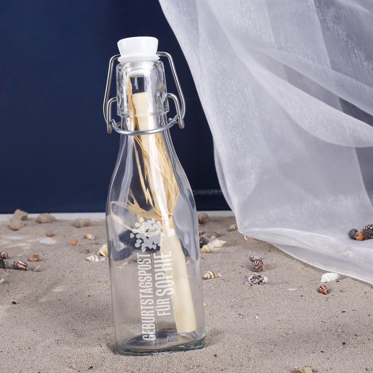 Glasflasche mit Bügelverschluss und eingerollter Geburtstagspost auf weißem Hintergrund als Geschenkidee