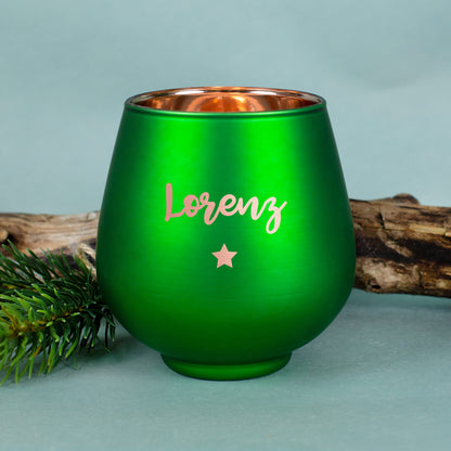 Grünes Windlicht mit Gravur „Lorenz“, auf hellblauem Hintergrund mit Tannenzweig.