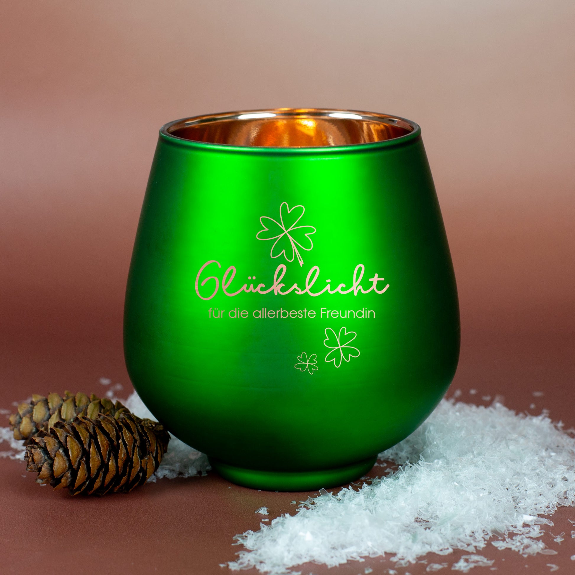 Grünes Windlicht mit Gravur „Glückslicht für die allerbeste Freundin“, dekoriert mit Zapfen und Kunstschnee