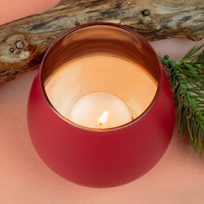 Detailaufnahme des roten Windlichts mit brennendem Teelicht und kupferfarbenem Innenreflex.