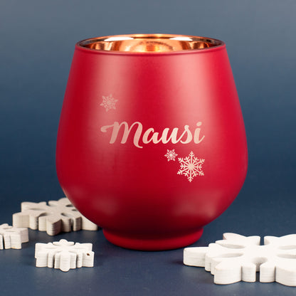 Rotes Windlicht mit Gravur „Mausi“ und Schneeflockenmotiv, auf dunklem Hintergrund mit weißen Schneeflocken-Dekoelementen arrangiert.